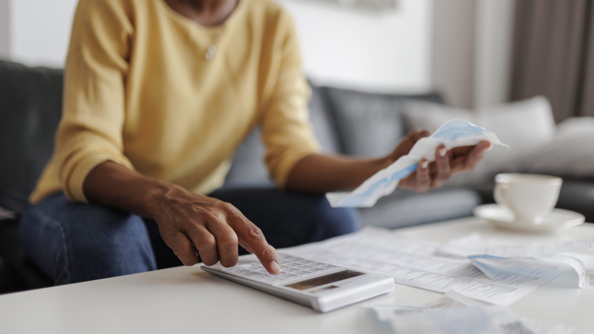 Close up of a mid adult woman checking her energy bills at home, sitting in her living room. She has a worried expression